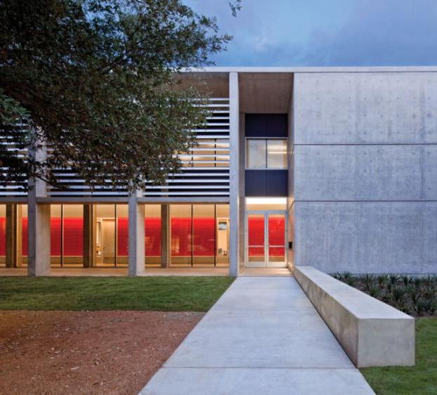 A view of Equity Hall and its courtyard at dusk, with the interior red walls illuminated by the hallway lights.