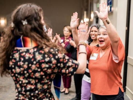 A human resources staff member high fives a student during a graduation celebration.