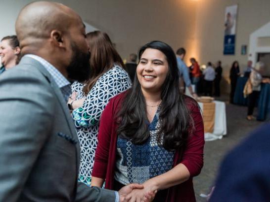 An alumna shakes hands with a board of trustee member.